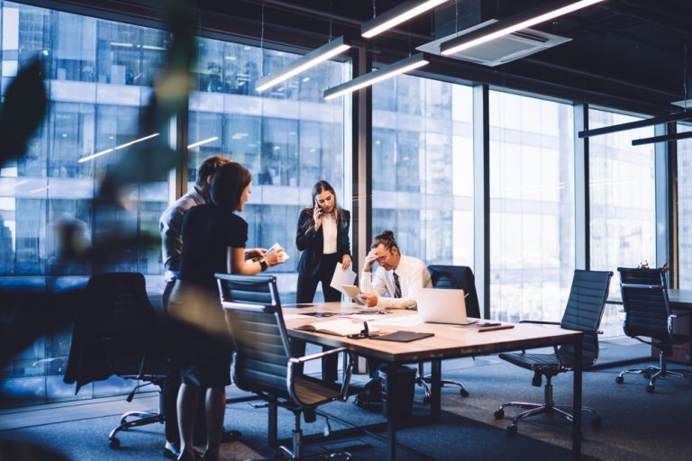 thoughtful team of colleagues using gadgets during meeting