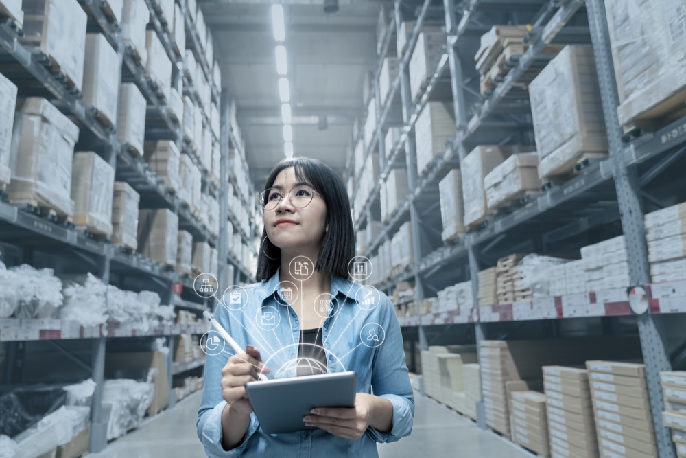 young attractive asian manager woman looking, picking, replemishment, receiving inventory at store warehouse in warehouse management system concept. smart erp with iot for inventory management.